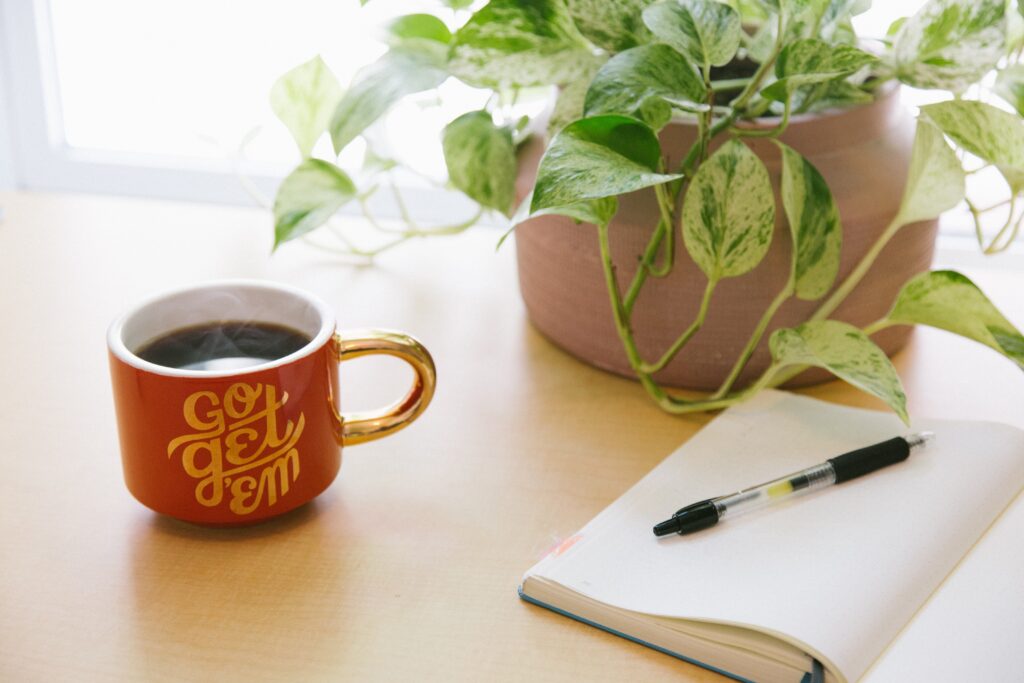 Content writer notes on a notepad next to a plant and mug of coffee